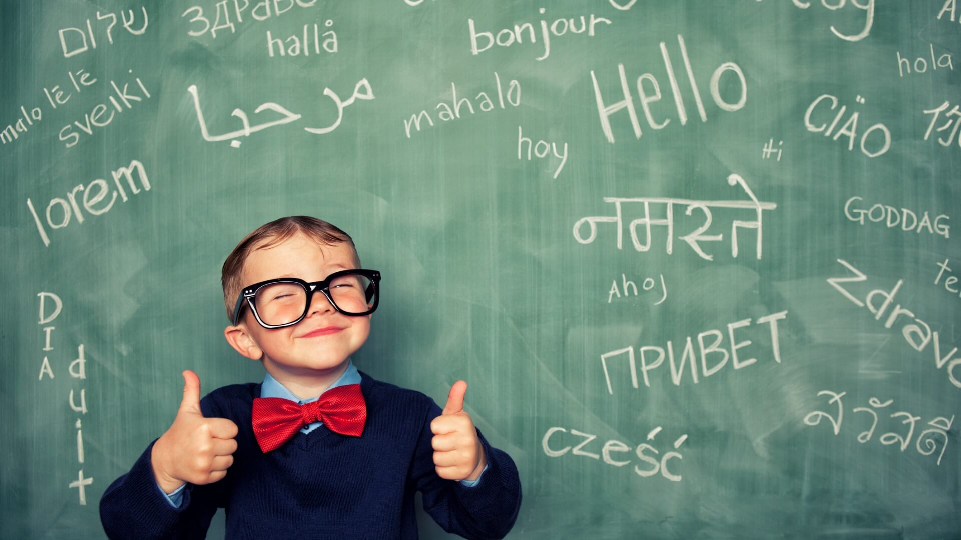 A kid in front of a chalkboard with different languages
